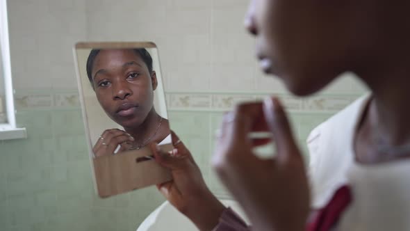 Reflection in Hand Mirror of Confident Slim African American Woman Admiring Beauty Smiling in Slow alt