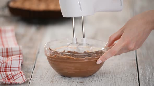 Whipping By a Mixer of Butter with Chocolate. Making Brown Chocolate Cream for the Cake.