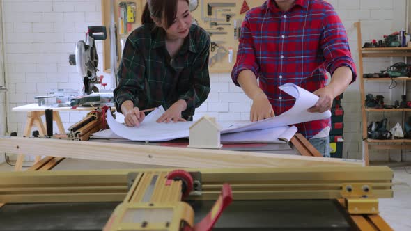 Two carpenters discussing and helping design a new wooden structure project