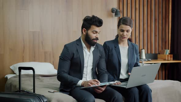 Girl and Guy in Suits Talking Looking at Laptop Screen in Modern Hotel Room alt