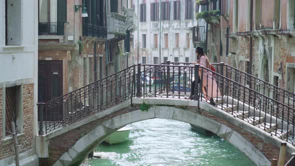 Woman Walks on Stairs of Stone Bridge Over Water Channel alt