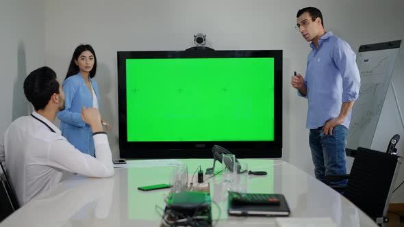 Confident Millennial Multiethnic Colleagues Discussing Project in Office with Green Screen Monitor alt
