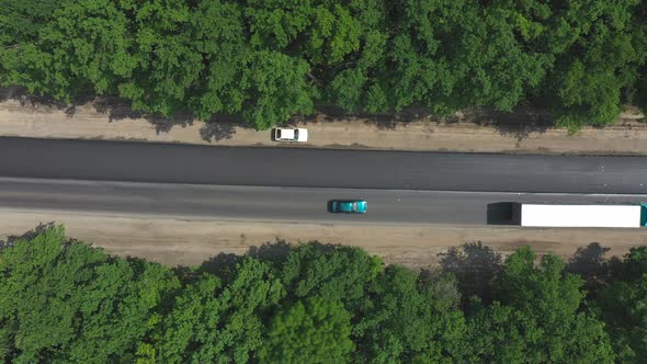 Aerial Shot of Car with Truck Driving on New Asphalt Road Through Forest alt