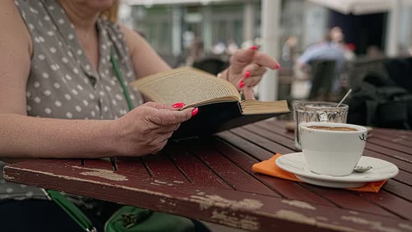 Woman is absorbed in reading an interesting book during a coffee break in a cafe