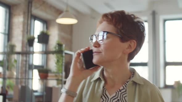 Businesswoman Having Phone Talk while Walking in Office alt