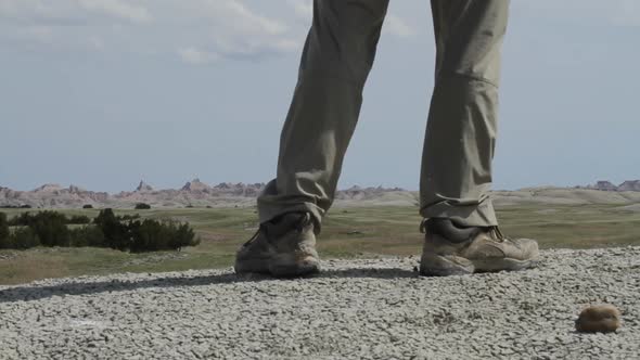 Hiker walks past camera and pauses - legs and boots visible - Badlands National Park, South Dakota alt