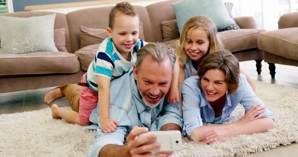 Happy family in lying on rug and talking a selfie on mobile phone alt