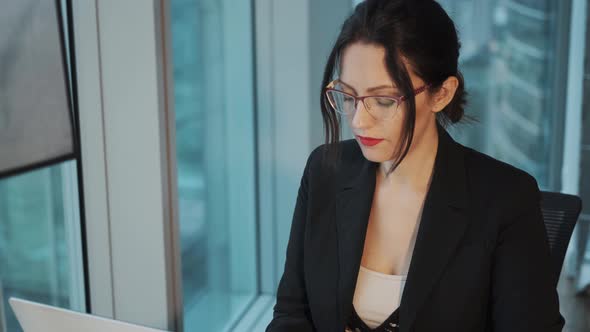 Portrait of an Attractive Business Woman Wearing Glasses Working at a Computer in a Modern Office alt