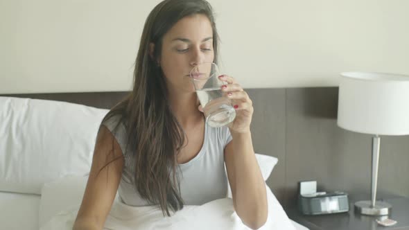 Woman taking birth control pill with glass of water