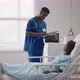 A Black Male Doctor is Talking to a Female Patient in a Hospital Ward - VideoHive Item for Sale