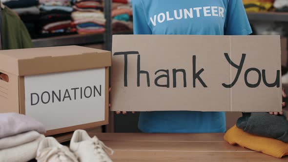Multiracial Woman Holding Banner with Thank you Phrase in Charity Shop alt