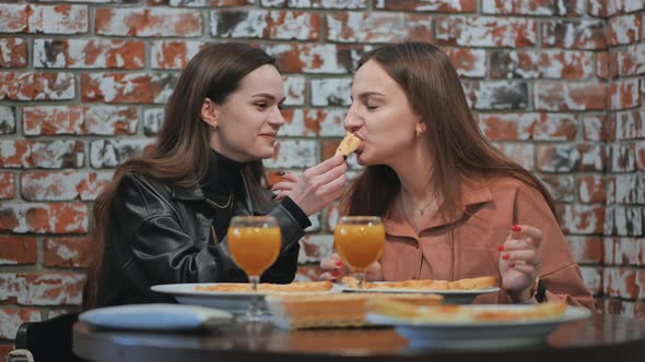 Young Girls Eat in a Cafe and Feed Each Other alt