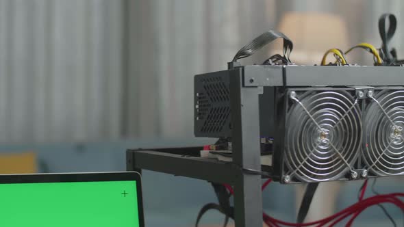 Close Up Of Green Screen Laptop And Mining Rig On The Table For Cryptocurrency Mining alt