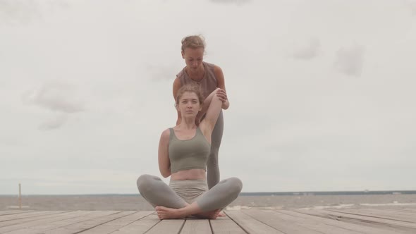 Young Woman Practicing Yoga Asanas with Coach Outdoors alt