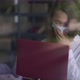Young Woman in Coronavirus Face Mask Coughing Surfing Internet on Laptop Sitting in Cafe Indoors - VideoHive Item for Sale