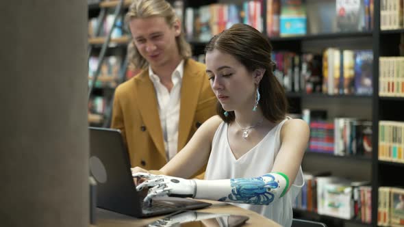 Girl and her boyfriend are working on laptop Bionics Cybernetic Robotic-arm Hand prosthesis alt