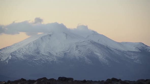 Time lapse of low clouds moving over snow-capped mountains in the Atacama Desert alt