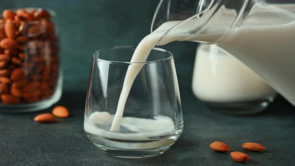 Pouring almond milk in glass. Vegan milk. Plant based milk replacer and lactose free. Alternative
