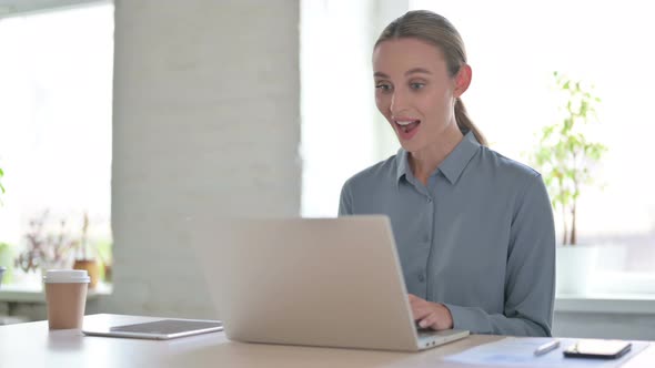 Woman Celebrating Success While Using Laptop in Office alt