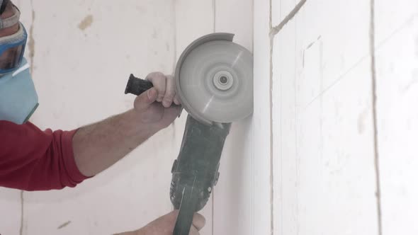 Handyman in Respirator and Goggles Cuts Wall with Disc Saw