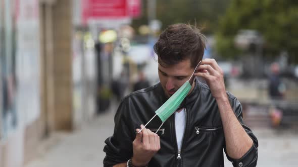 A young man with a cool hairstyle wearing a black jacket and a white t-shirt, putting on a green pro alt