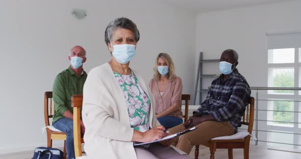 Two diverse senior couples sitting in circle having therapy conversation at home looking at camera alt