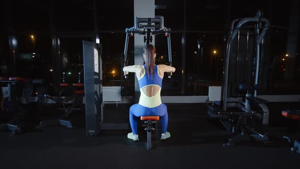 Attractive Woman Athlete Doing Workout Training Hands Chest and Her Back on Weights Exercise Machine alt