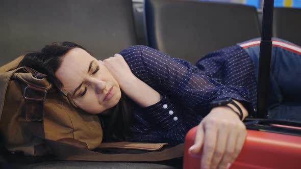 The Tired Woman Sleeps in the Terminal of the Airport