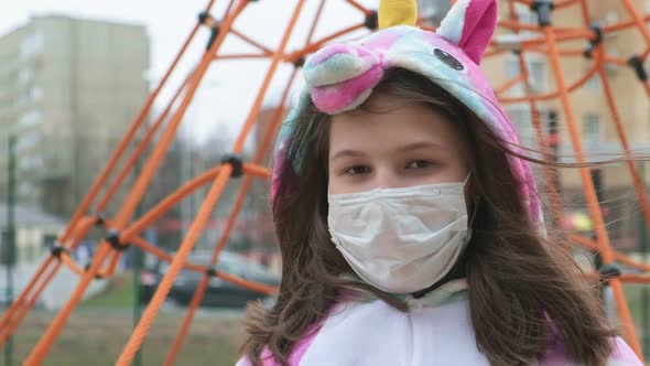 Young Girl in a Protective Mask at the Playground