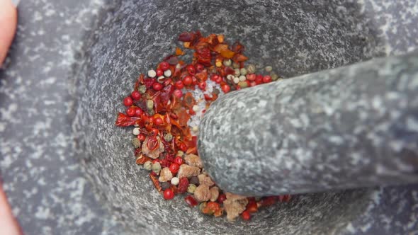 Super Closeup of Heavy Pestle Starting to Grind Mix of Spices and Peppers alt