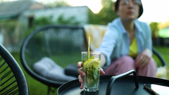 Happy Woman in Glasses Sitting on Chair at Backyard Outdoor at Home Take Lemonade