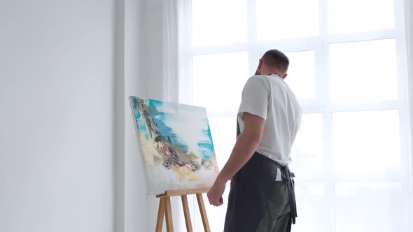 The Artist Paints an Abstract Picture He is Focused on Work Painting on an Easel in His Art Studio alt