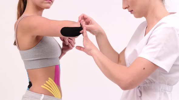 Professional glues tapes on a woman's elbow. Young fit women showing on her elbow alt
