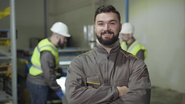 Portrait of Confident Caucasian Man Looking at Camera and Smiling. Foreman with Black Hair and Beard alt