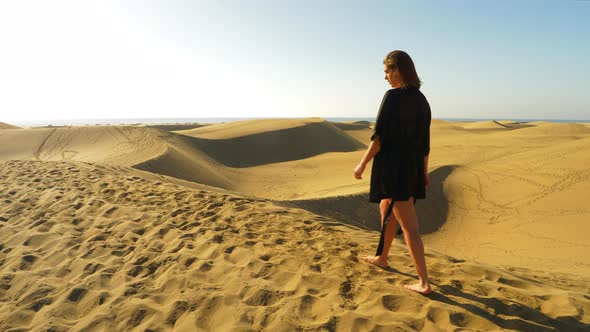 Elegant Model in Black Coverup Walking Barefeet with a View of Sand Dunes alt