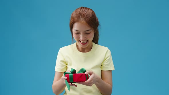 Young Asia girl smile and receiving present box isolated over blue background.