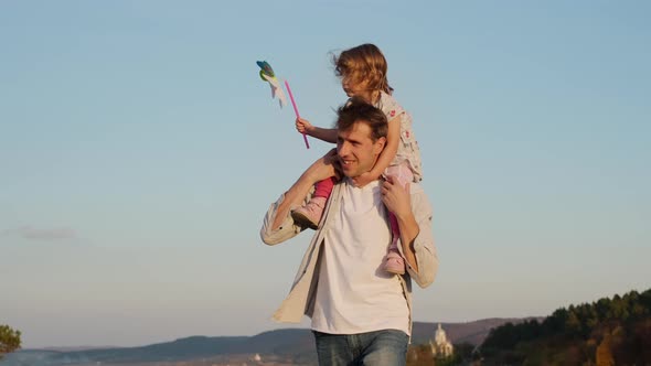 Family Vacation In Nature. Daughter Sits On The Back Of Her Father. alt