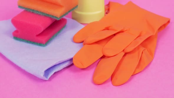 On a Pink Background a Plastic Bottle of Cleanser and Orange Latex Gloves