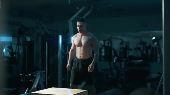 A Handsome Young Muscular Sportsman is Doing Exercise on a Fitness Machine in the Gym alt