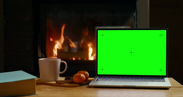 Laptop with Chromakey Green Screen at Fireplace in Cozy Winter Home Office