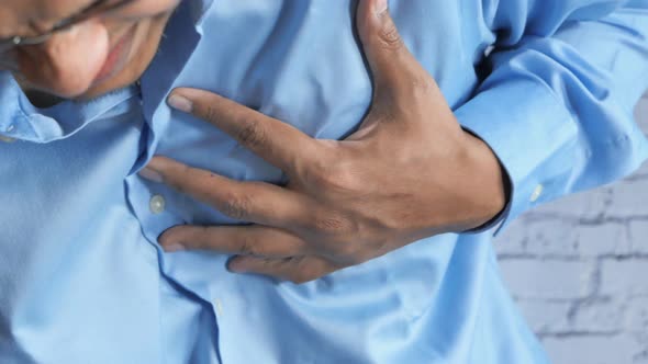 Young Man Suffering Pain in Heart and Holding Chest with Hand  alt