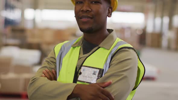 Portrait of african american male worker wearing safety suit and smiling in warehouse alt