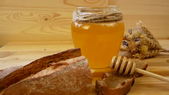 Honey and Bread with a Wooden Spoon on the Table