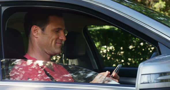 Man using mobile phone in the front seat of car alt