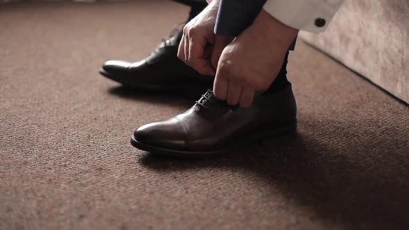 Businessman Man Ties Shoelaces on Brown Boots in a Room. A Man Wears Shoes.