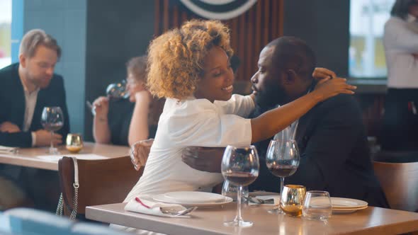 Portrait of Romantic Afro-american Couple Embracing on Date in Restaurant alt