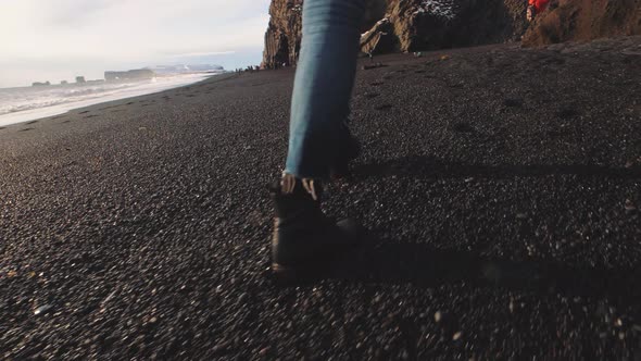 Traveler Woman Walking on Volcanic Black Sand Beach in Iceland alt