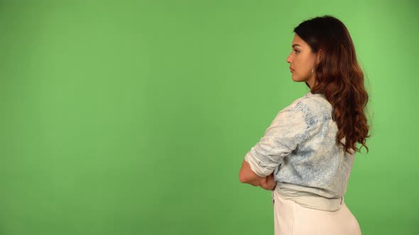 A Young Beautiful Caucasian Woman Looks Around As She Faces the Green Screen Background