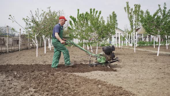 Man Plowing the Land in the Garden on Sky Background