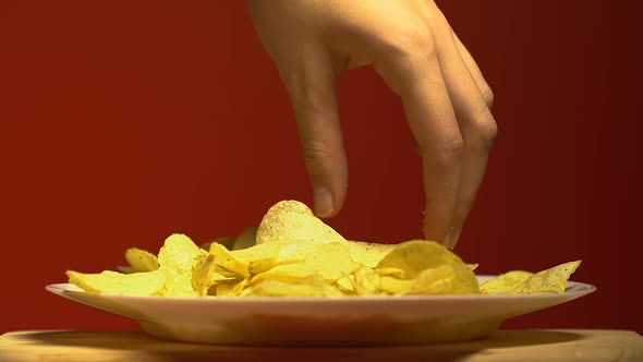 Womans Hand Slowly Taking One Piece of Chips, Junk Food Addiction, Close Up alt